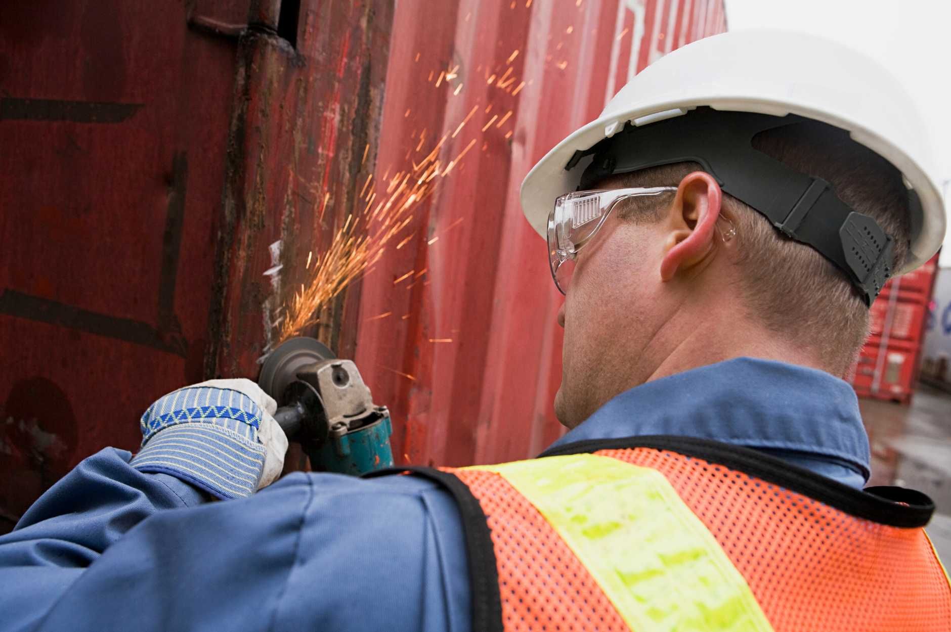 Man making sparks with power tool while working on container