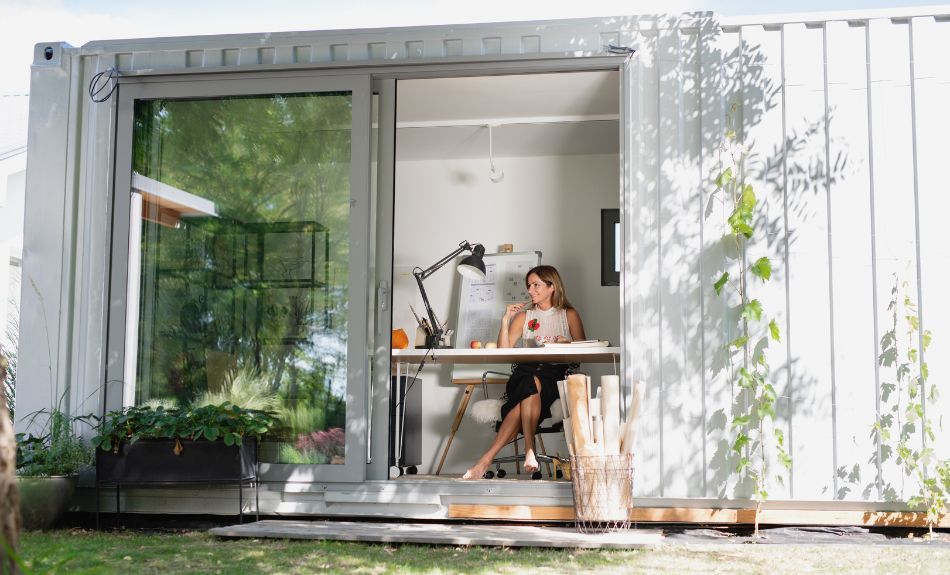 Woman sitting in backyard office made from shipping container