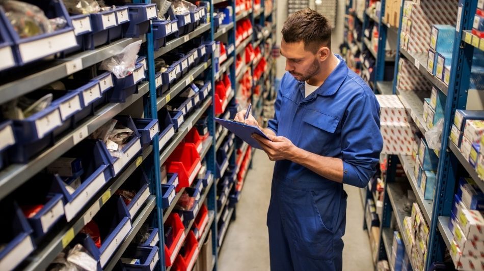 Man with clipboard looking at wall of categorized automotive parts