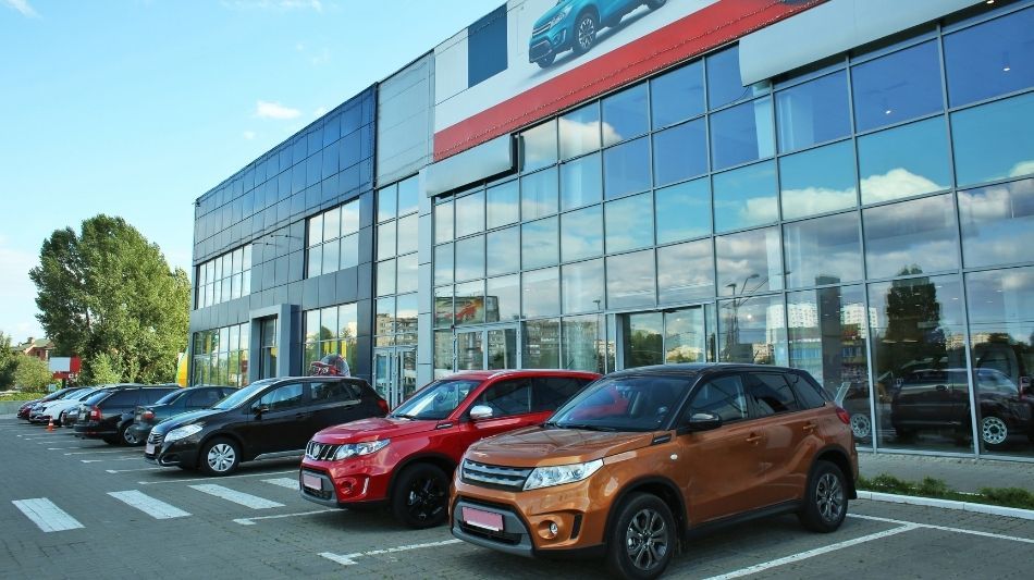 Row of new cars sitting outside of car dealership
