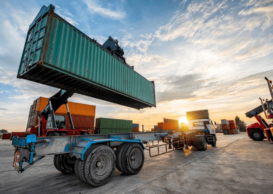 Crane taking shipping container off flatbed truck