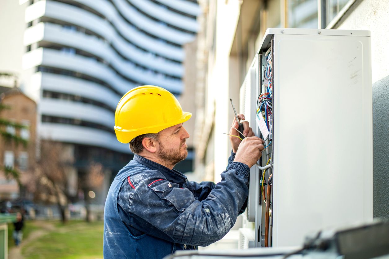 Electrical construction worker with yellow hard hat working on electrical box