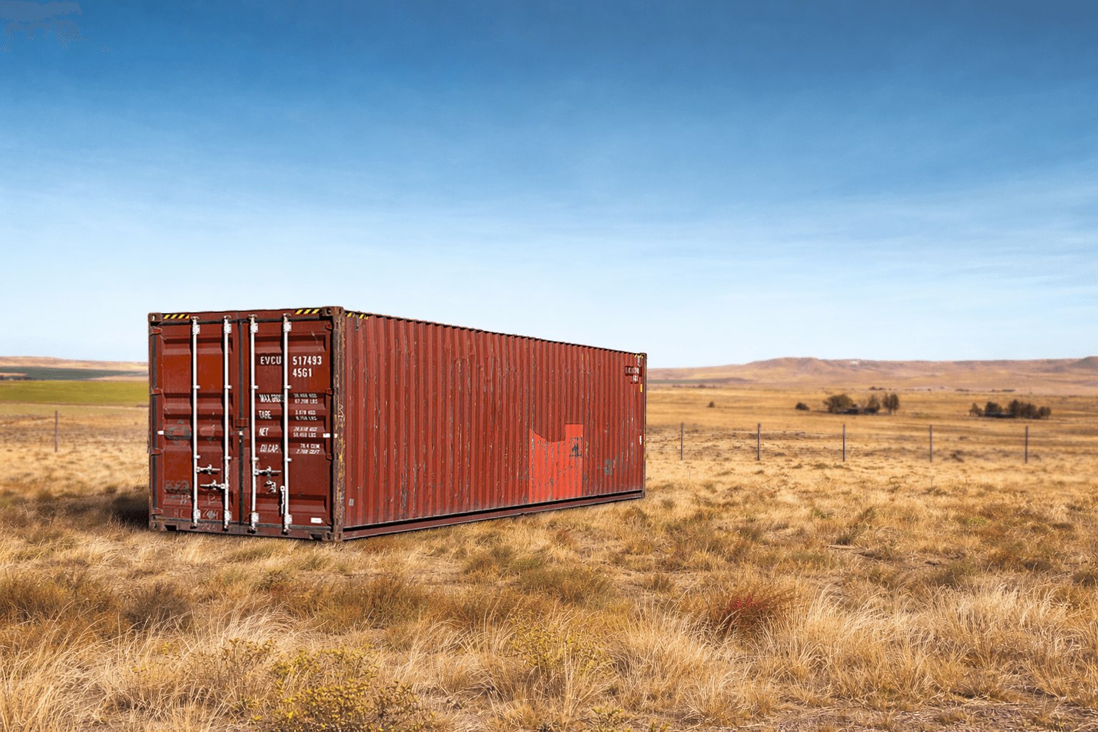Red shipping container in a field