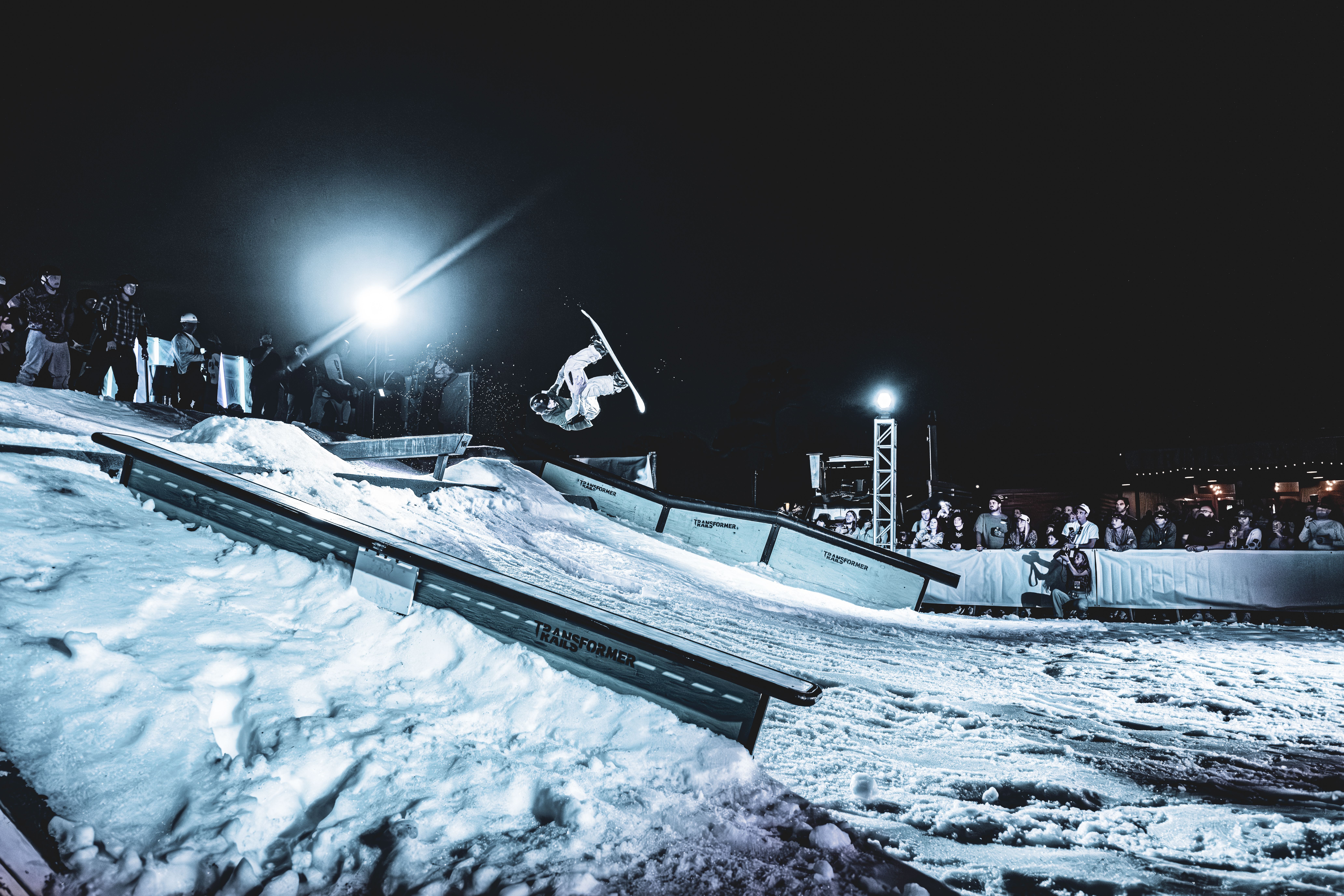 Snowboarder doing flip on a custom-built ramp elevated by several 20ft used containers