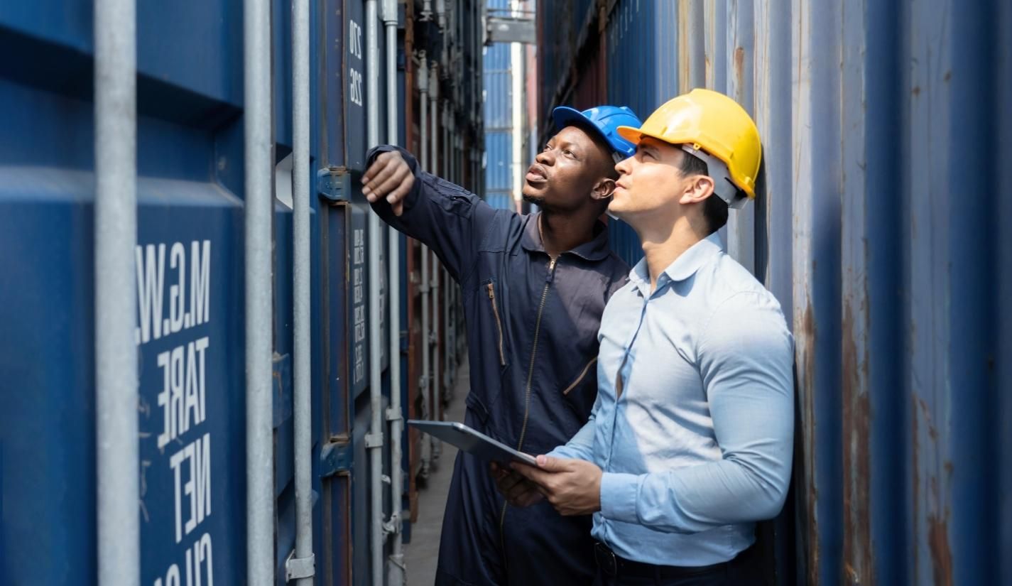 Two men in hardhats inspecting outside of used shipping container